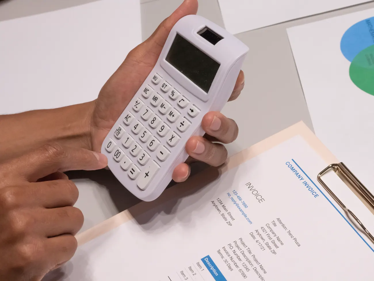 Hands holding a calculator over a printed invoice