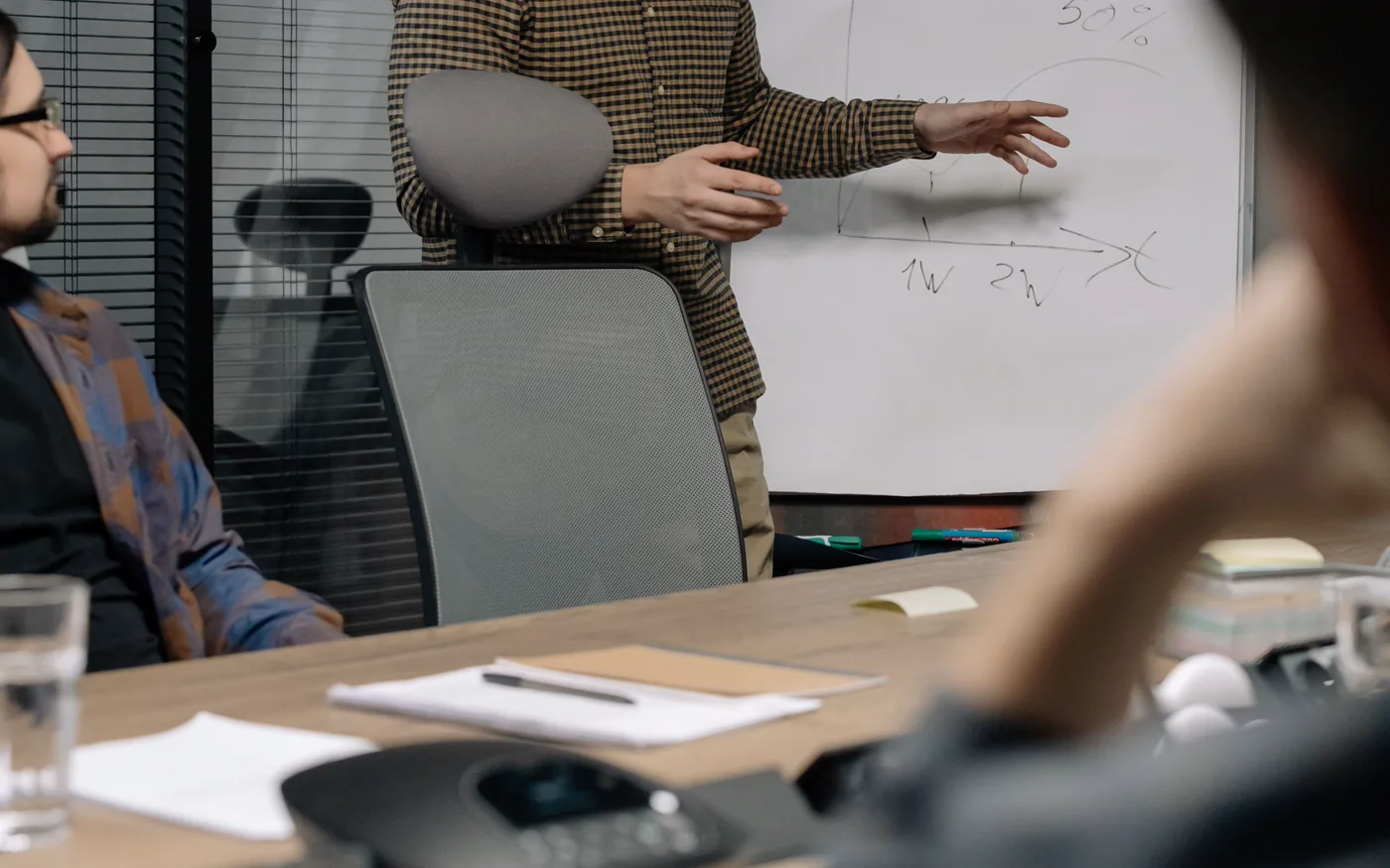 A manager explaining a chart on a whiteboard to a seated team