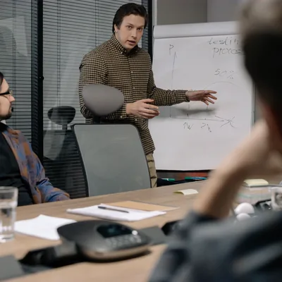 A manager explaining a chart on a whiteboard to a seated team