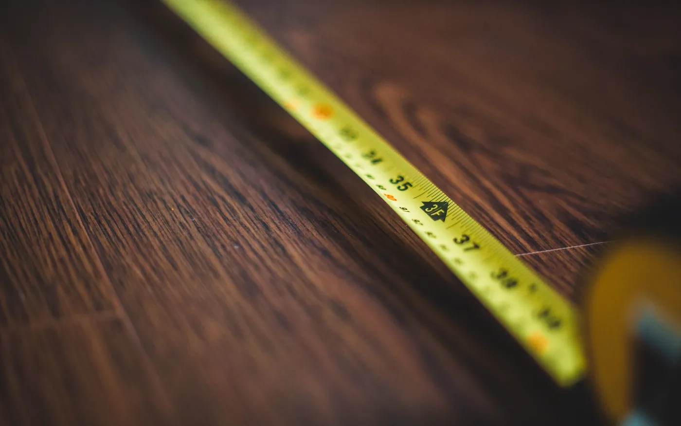 Un ruban à mesurer déroulé sur un plancher de bois foncé