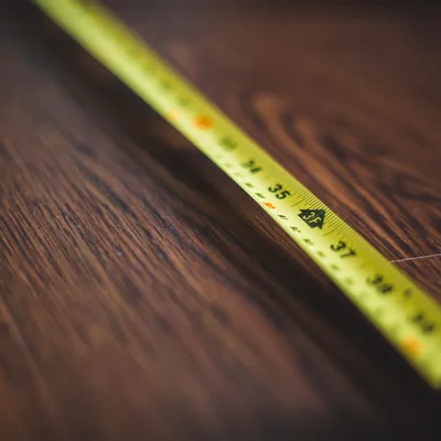 A tape measure stretched across a dark wooden floor