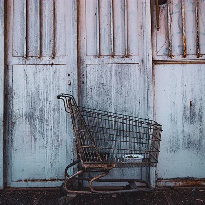 An abandoned shopping trolley against a weathered wall