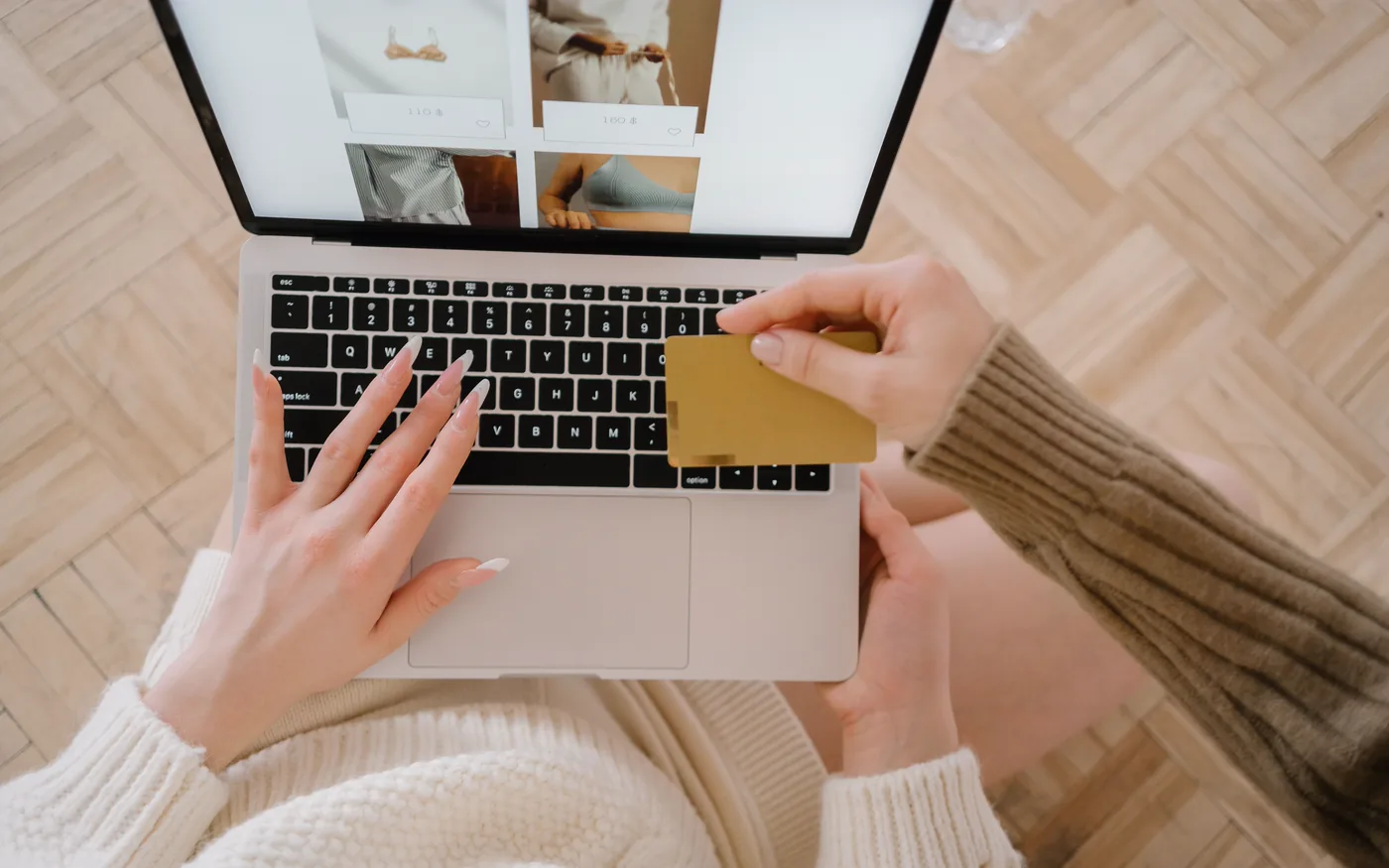 A shopper holding a bank card while browsing a store on a laptop