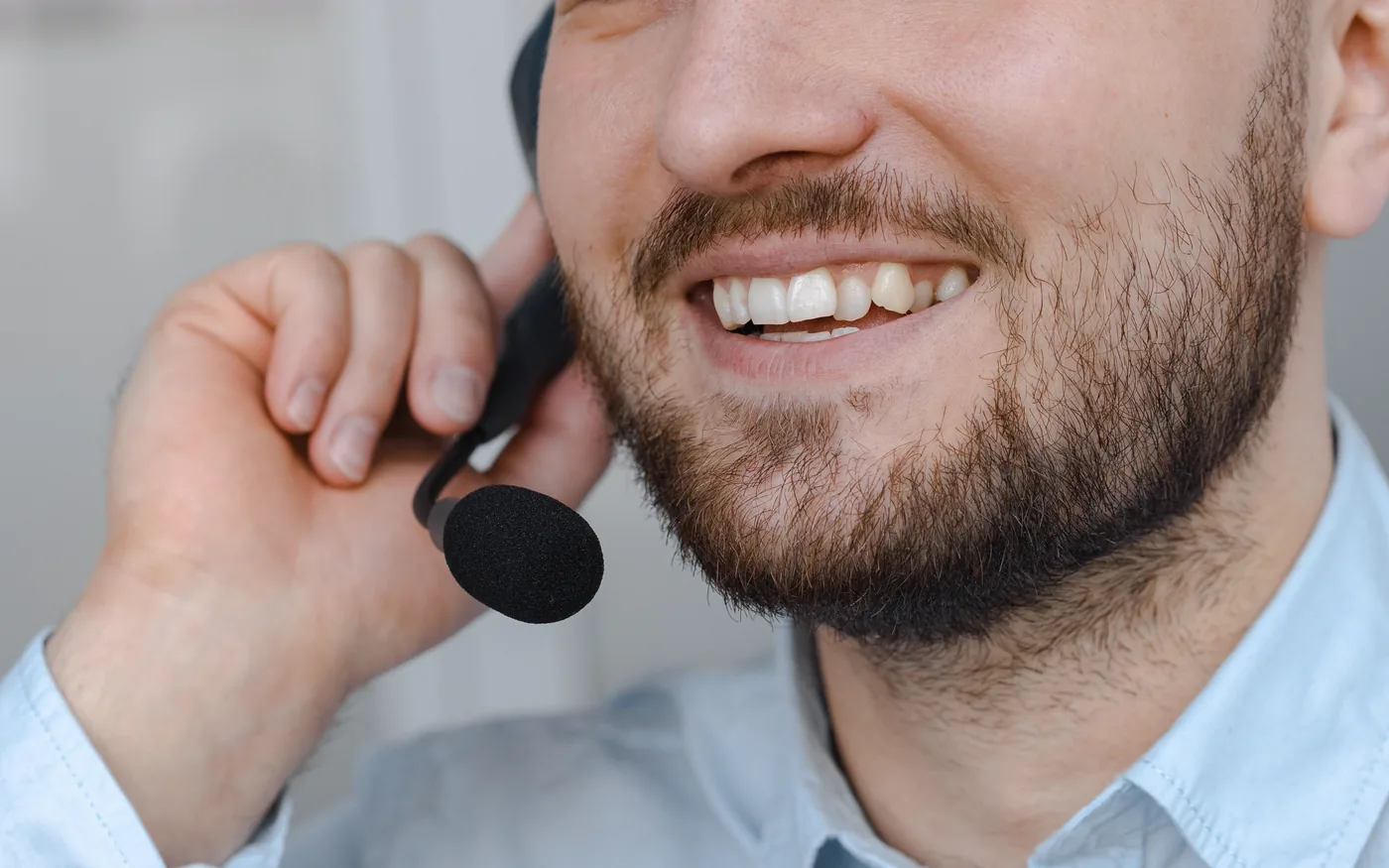 A smiling advisor holding the earpiece of a headset