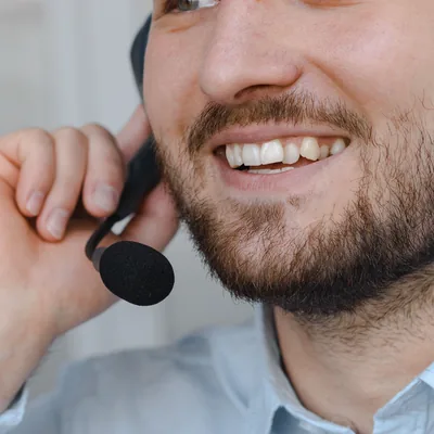 A smiling advisor holding the earpiece of a headset