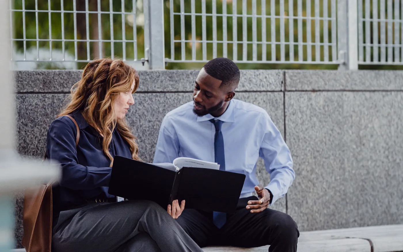 Two colleagues on a bench going through a folder together