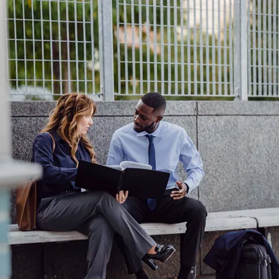 Two colleagues on a bench going through a folder together