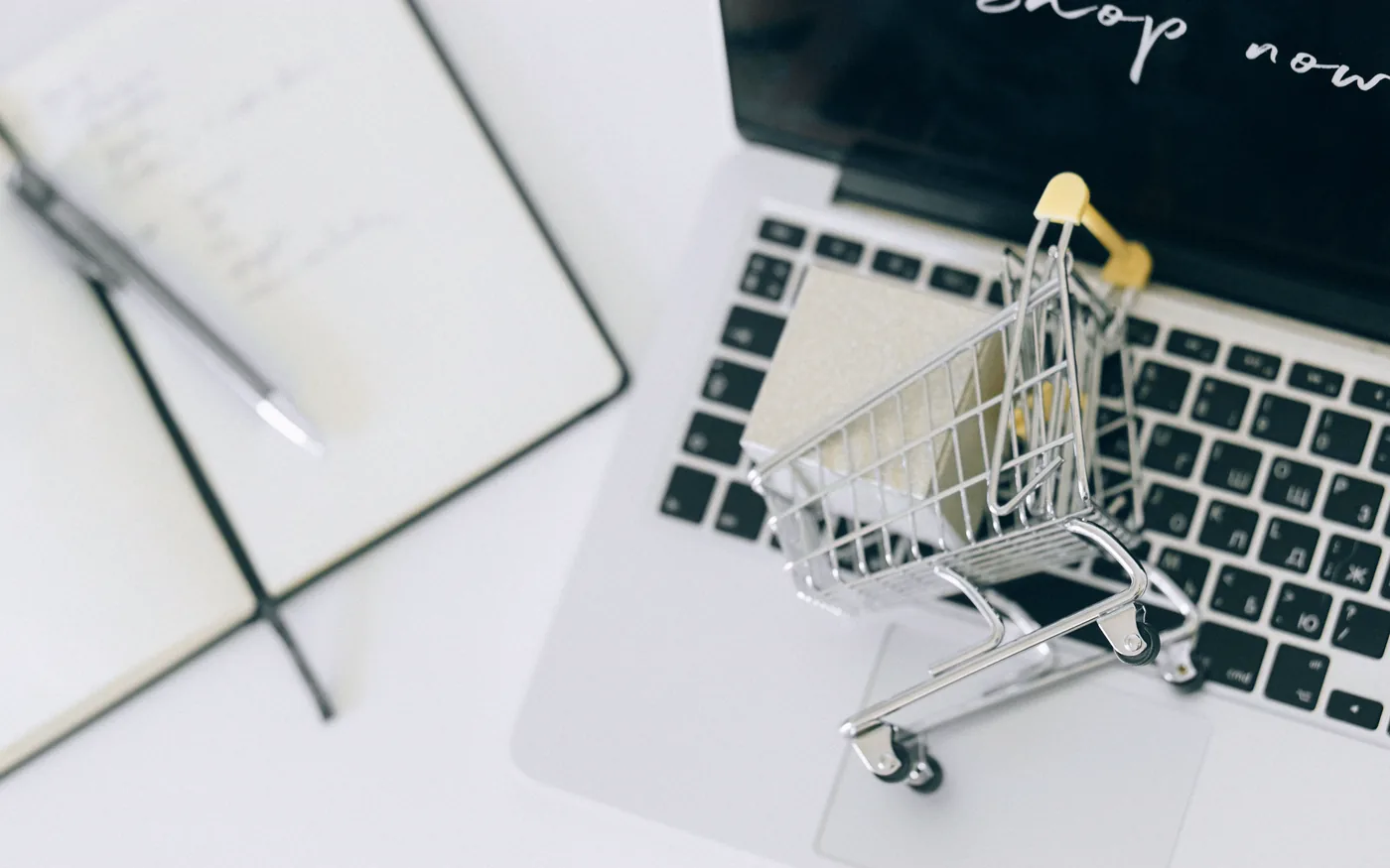 A miniature shopping trolley resting on a laptop keyboard