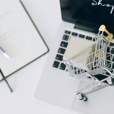 A miniature shopping trolley resting on a laptop keyboard