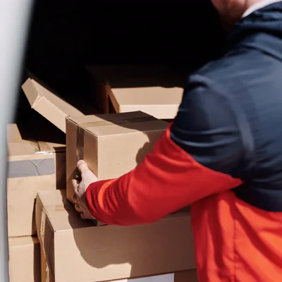 Un livreur empilant des colis scellés dans une camionnette de livraison