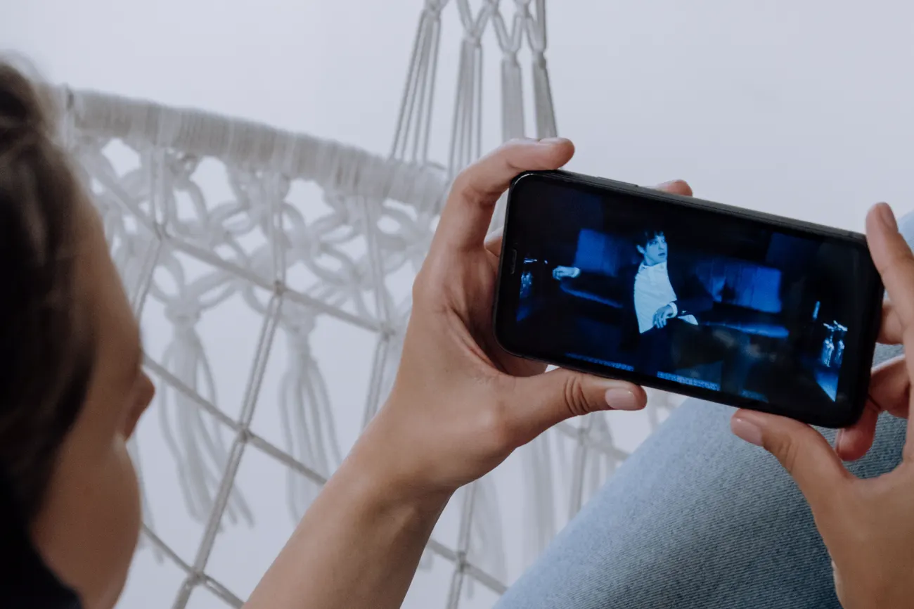 A person holding a smartphone sideways to watch a video