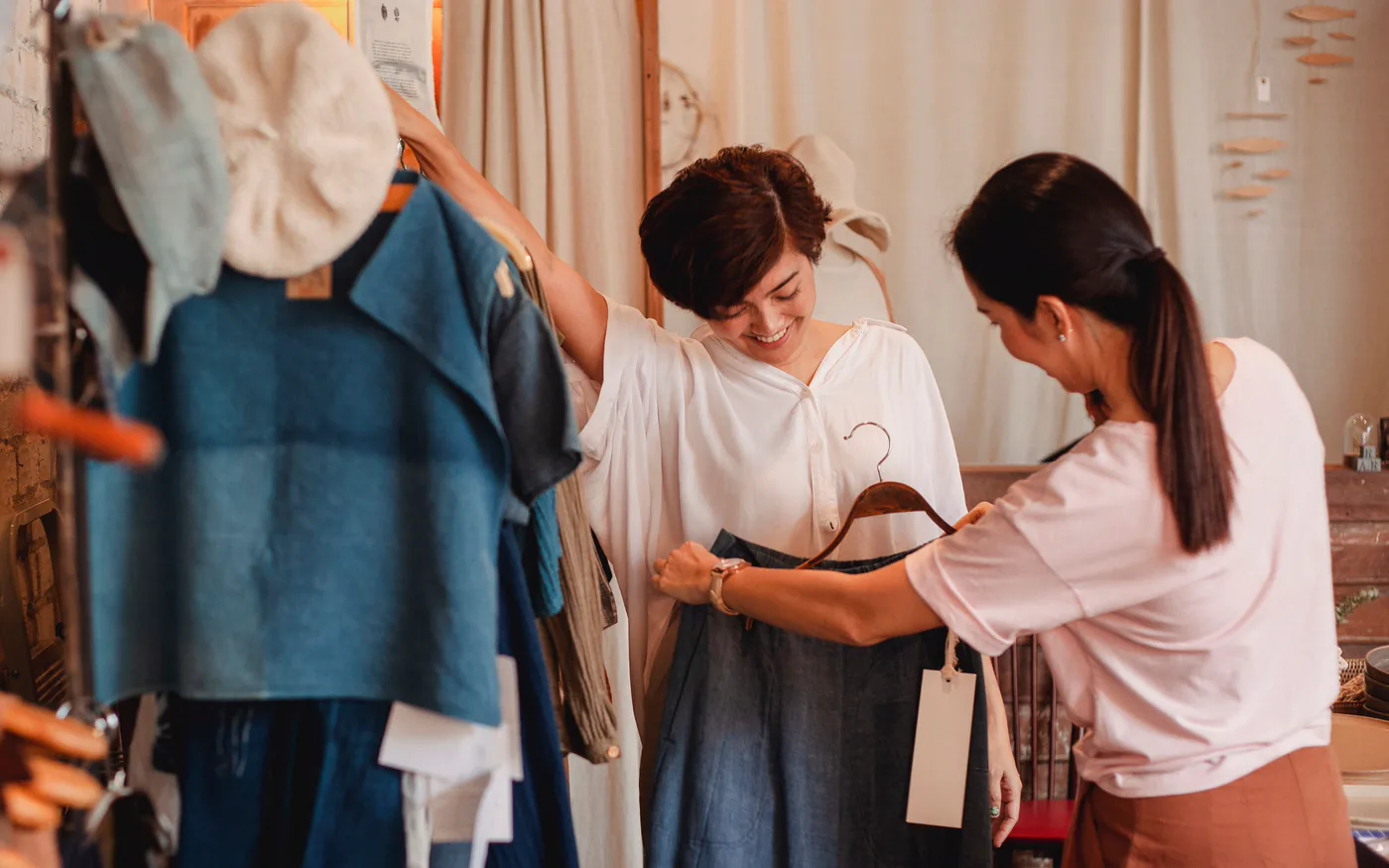 A shop assistant showing a garment on a hanger to a customer