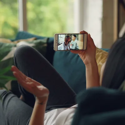 Someone on a sofa taking a video call on a phone